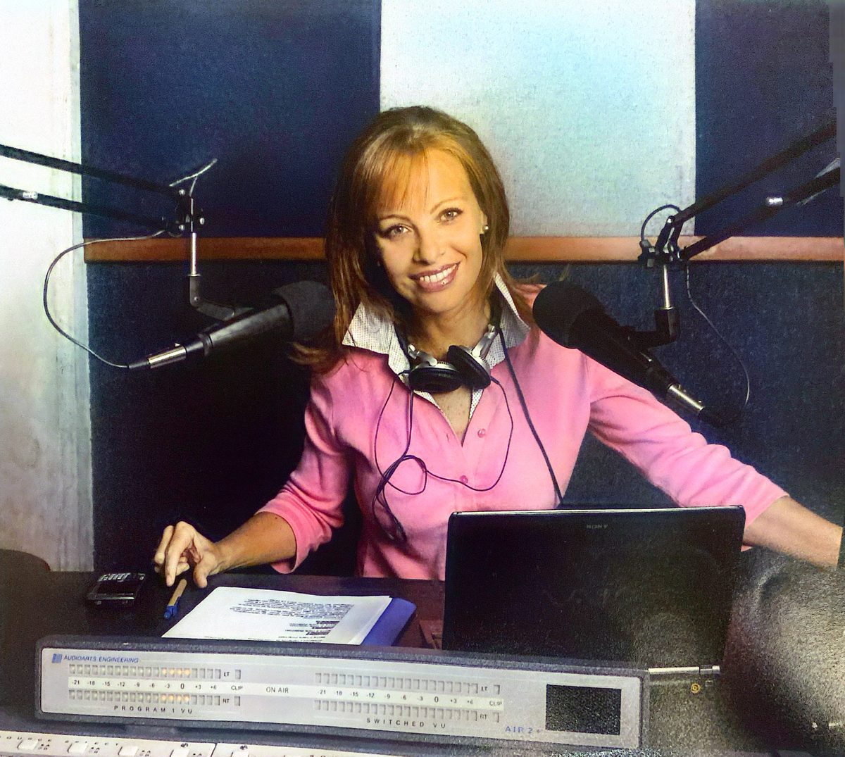 Hannah Zea sonriendo en un estudio de radio, entre micrófonos y consola